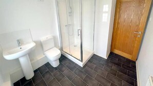 A bathroom with a glass-enclosed shower, a pedestal sink, and a toilet.