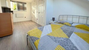 Ein Schlafzimmer mit Bett, Schminktisch, Fenster und Tür.