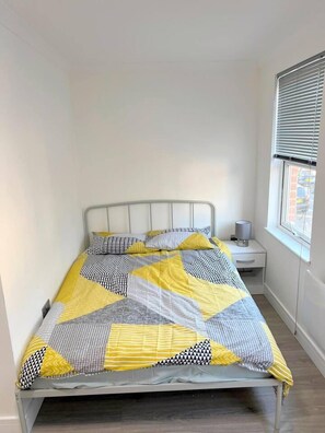 A bed with a geometric patterned bedspread in yellow, gray, and black.