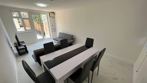 Ein stilvoller Essbereich mit einem langen Tisch, sechs Stühlen, einer Couch und einem kleinen Tisch für den Fernseher.