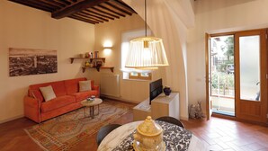A living room with a sofa, a table with a decorative pot, a patterned rug, a hanging lamp, and a view through a glass door. - Siena UP Town: Sabrina's Lovely apartment (Siena)