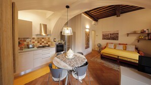 A cozy room with a dining table, chairs, a bed, and a kitchen area. - Siena UP Town: Sabrina's Lovely apartment (Siena)