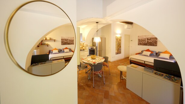 A compact living space with a dining area, kitchenette, and a bed with a desk. - Siena UP Town: Sabrina's Lovely apartment (Siena)
