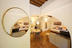 Un espacio habitable compacto con comedor, kitchenette y una cama con escritorio.