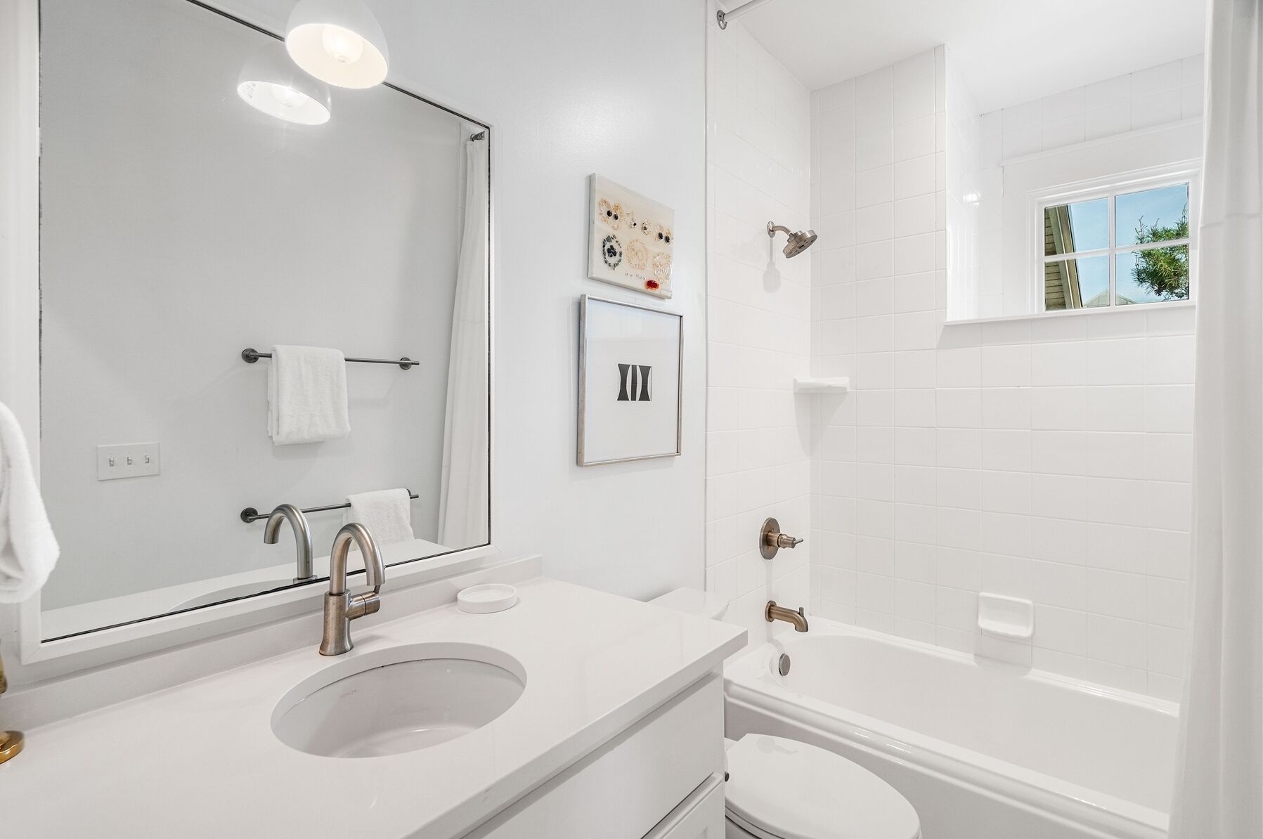Une salle de bain moderne avec un grand miroir, deux lavabos, des toilettes et une baignoire.