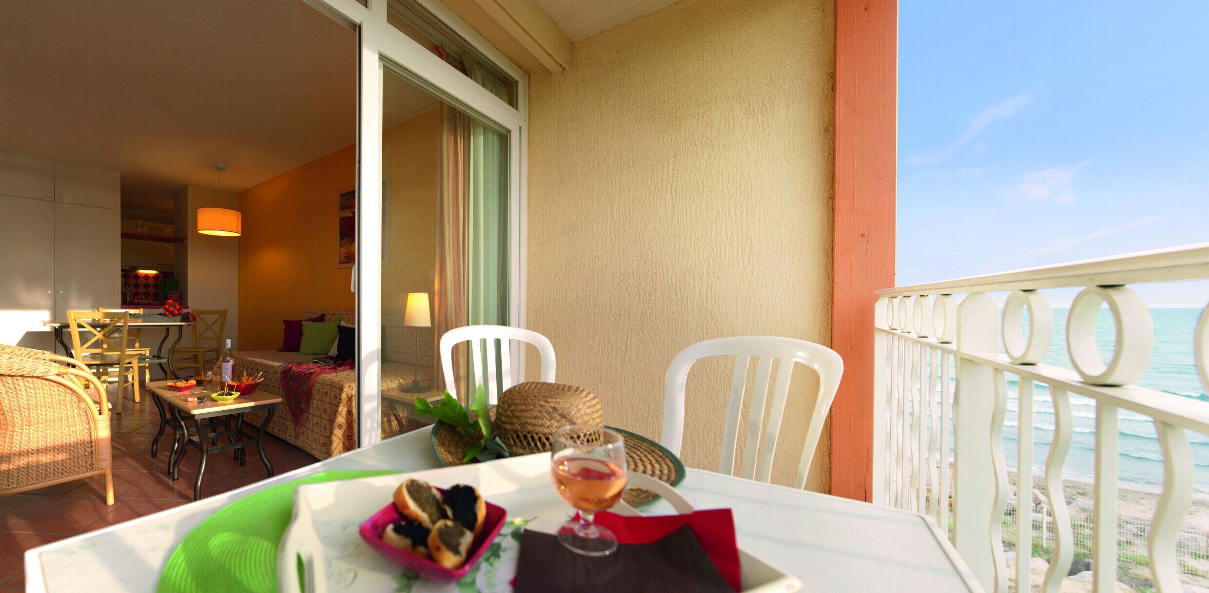 Een balkon met een eettafel, stoelen en uitzicht op zee.