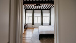 A bedroom with a bed, a desk, and a window with curtains. - Gorgeous Duplex Apartment in old City Centre (Antwerp)