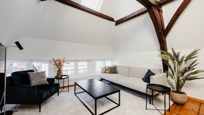 A modern living room with a dark sofa, a light-colored sofa, a black coffee table, and a potted plant. - Gorgeous Duplex Apartment in old City Centre (Antwerp)