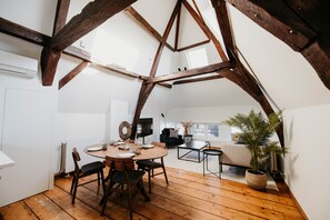 A dining area with a wooden table and chairs, a television, and a potted plant. - Gorgeous Duplex Apartment in old City Centre (Antwerp)
