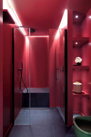 A modern bathroom with a glass-enclosed shower, red walls, and a green chair. - Agorà - Boutique Stays (Turin)