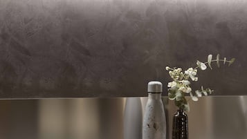 Eine Küchenarbeitsplatte mit modernem Design, ausgestattet mit einer Edelstahl-Dunstabzugshaube, einer Vase mit Blumen und einer Wasserflasche.