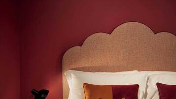 A neatly made bed with a headboard, a bedside table with a lamp, and a wall with a textured pattern.