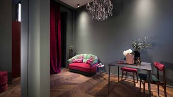 A modern room with a herringbone wood floor, a red sofa, a dining table with chairs, and a chandelier.