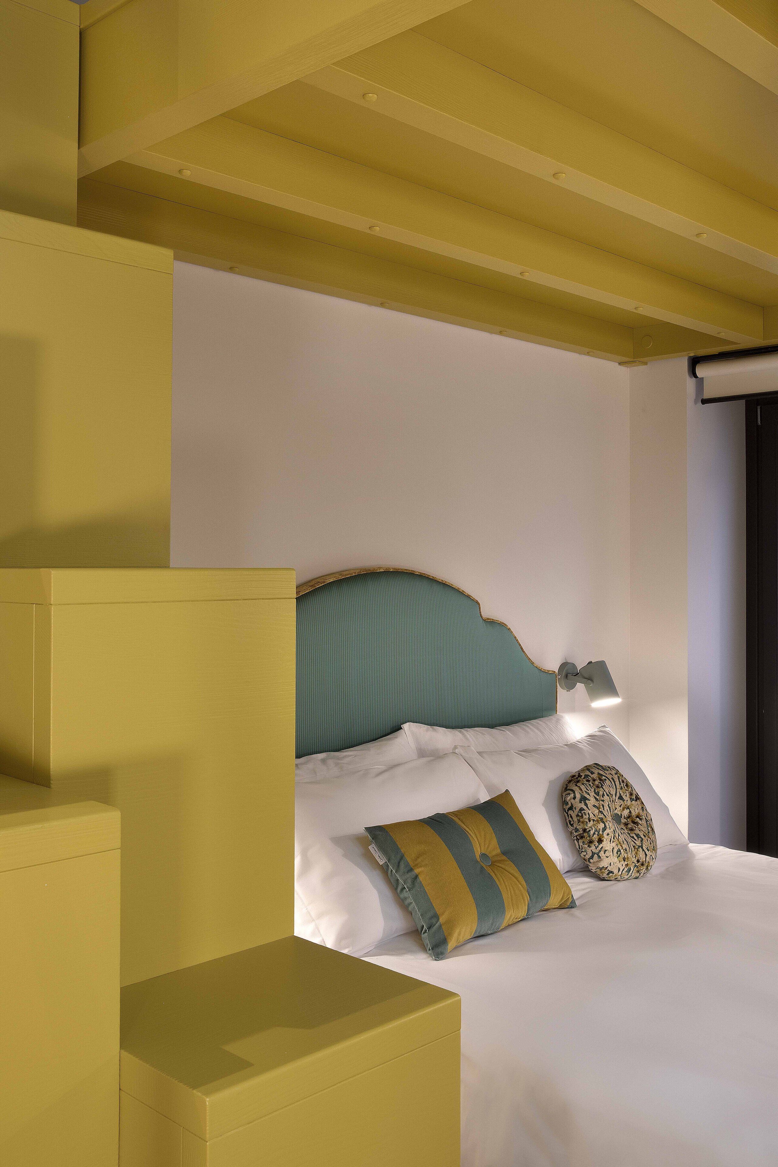 A bed with a headboard, pillows, and a bedside lamp.