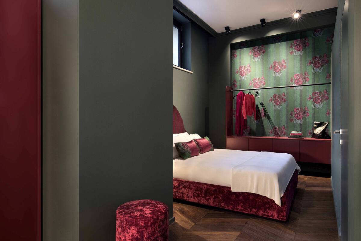 A modern bedroom with a large bed, a vanity with a mirror, and a red upholstered stool.