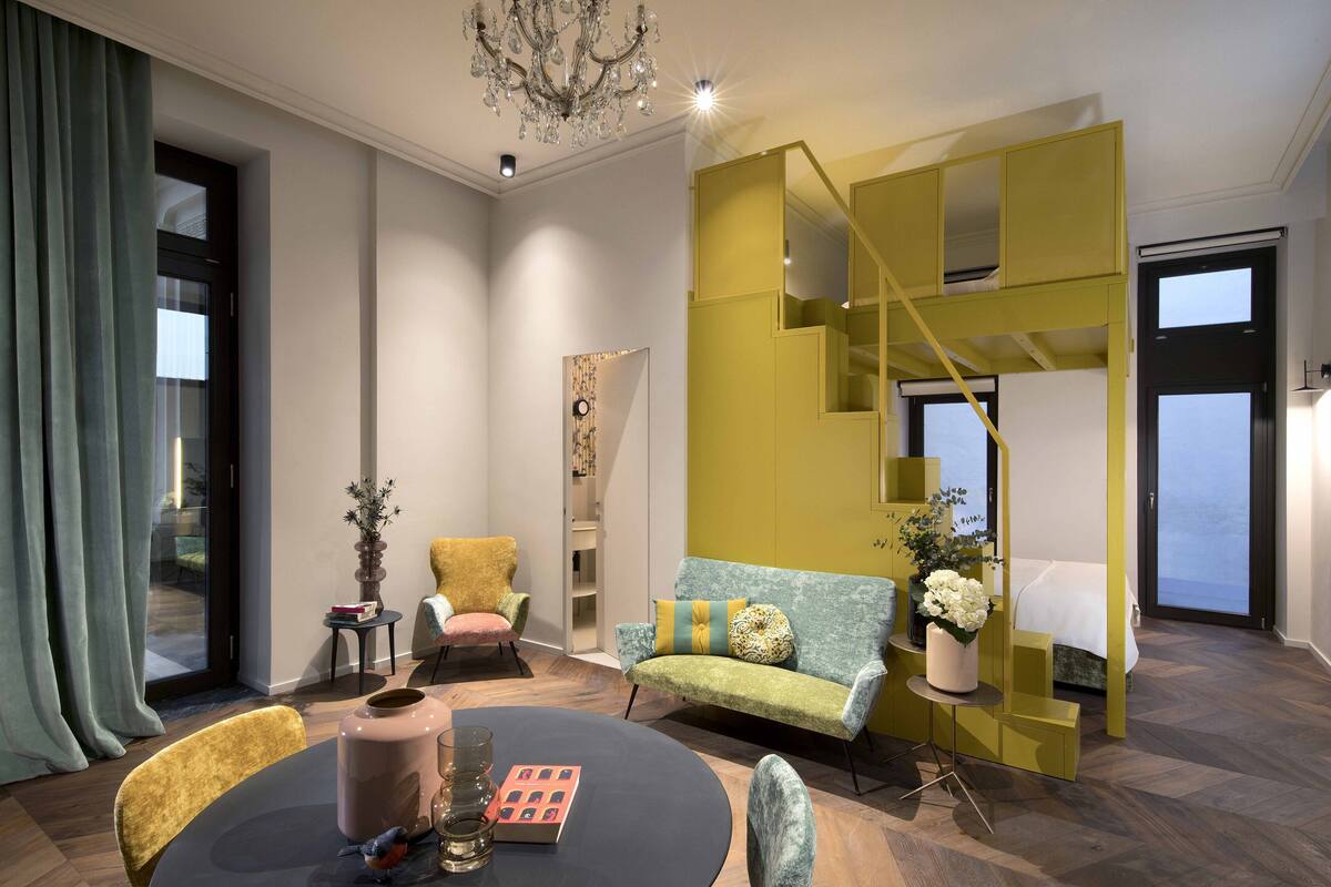 A modern living room with a round table, a sofa, and a staircase with yellow accents.