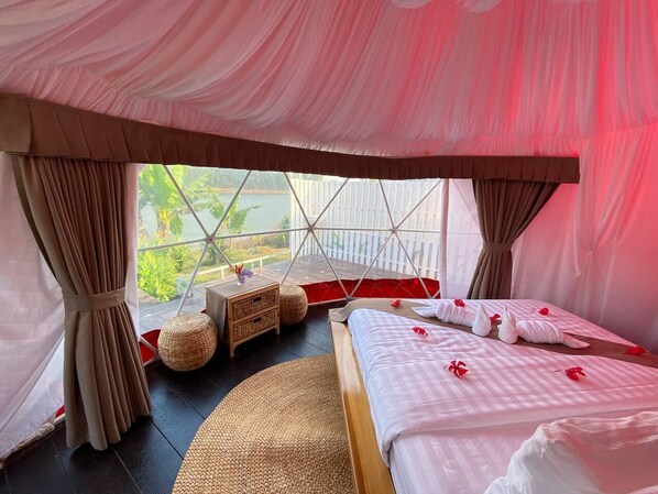 Una habitación con cama, una mesita y vistas al verde exterior.