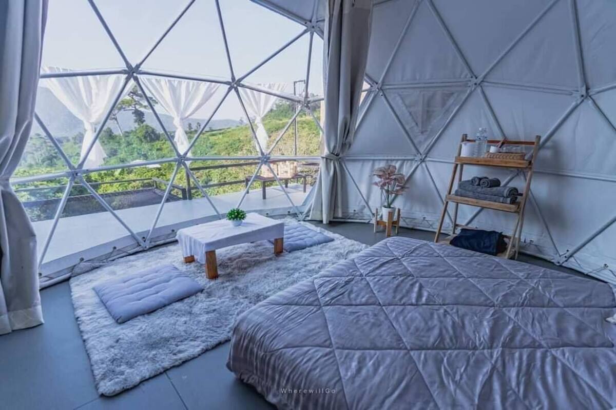 Une pièce spacieuse avec un grand lit, une petite table et une étagère remplie d’objets.