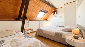 Ein Schlafzimmer mit zwei Betten, einem Oberlicht, einer Heizung und einem kleinen Fenster.