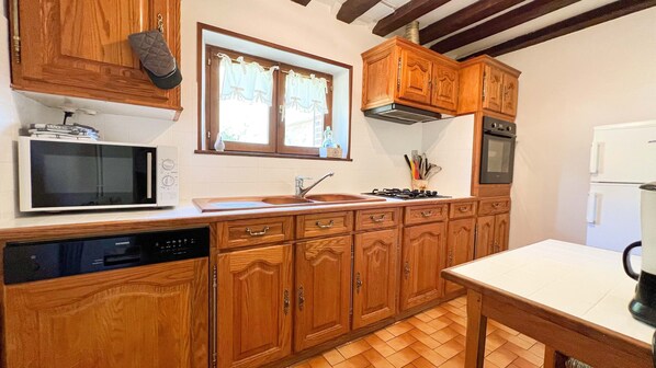 Una cocina con armarios de madera, microondas, lavavajillas, fregadero y estufa.
