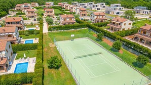 An aerial view of a residential area with multiple houses, a tennis court, and a swimming pool. - Villa LiLi Apt 3 Studio (Poreč)