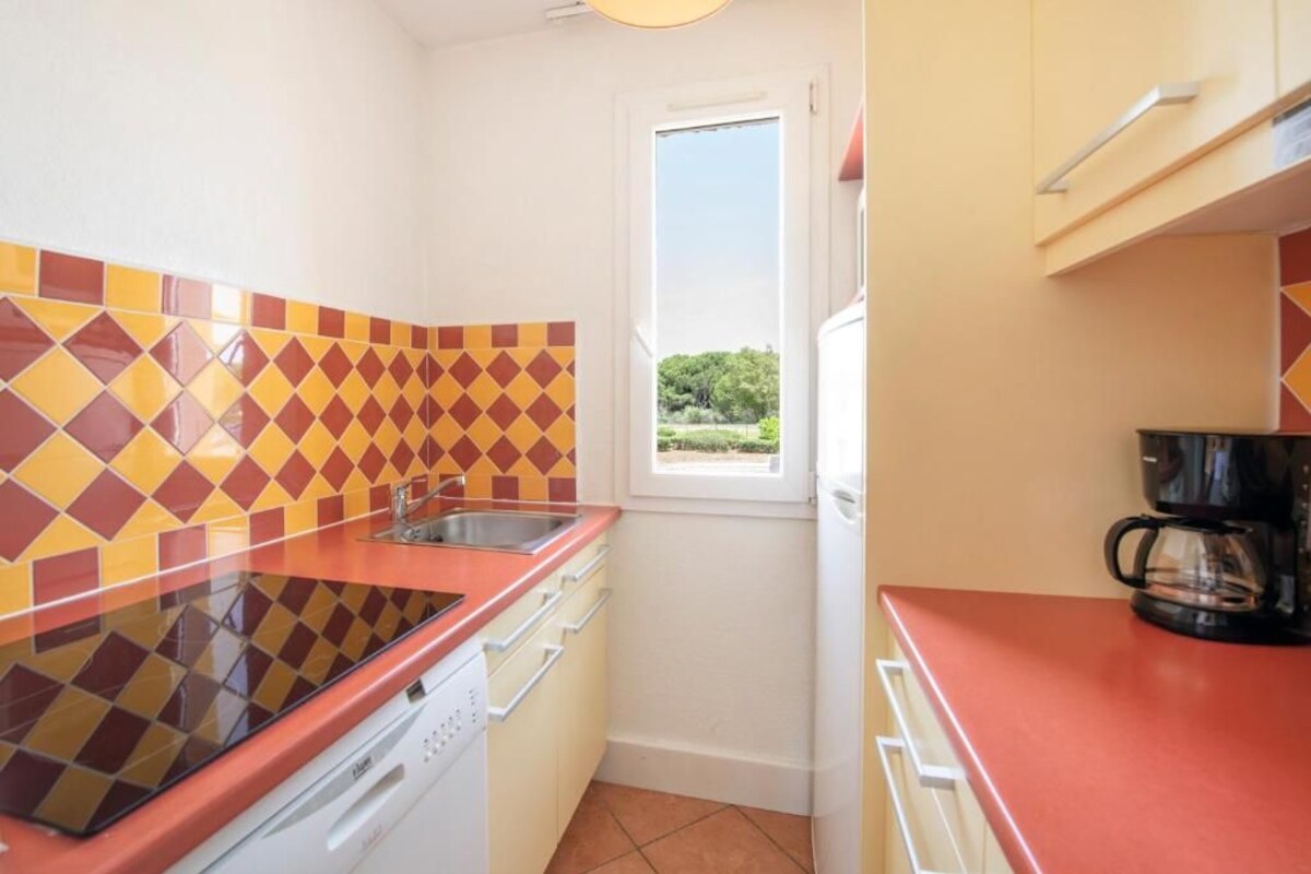 Una cocina compacta con encimera roja, un fregadero y una ventana con vistas a zonas verdes.
