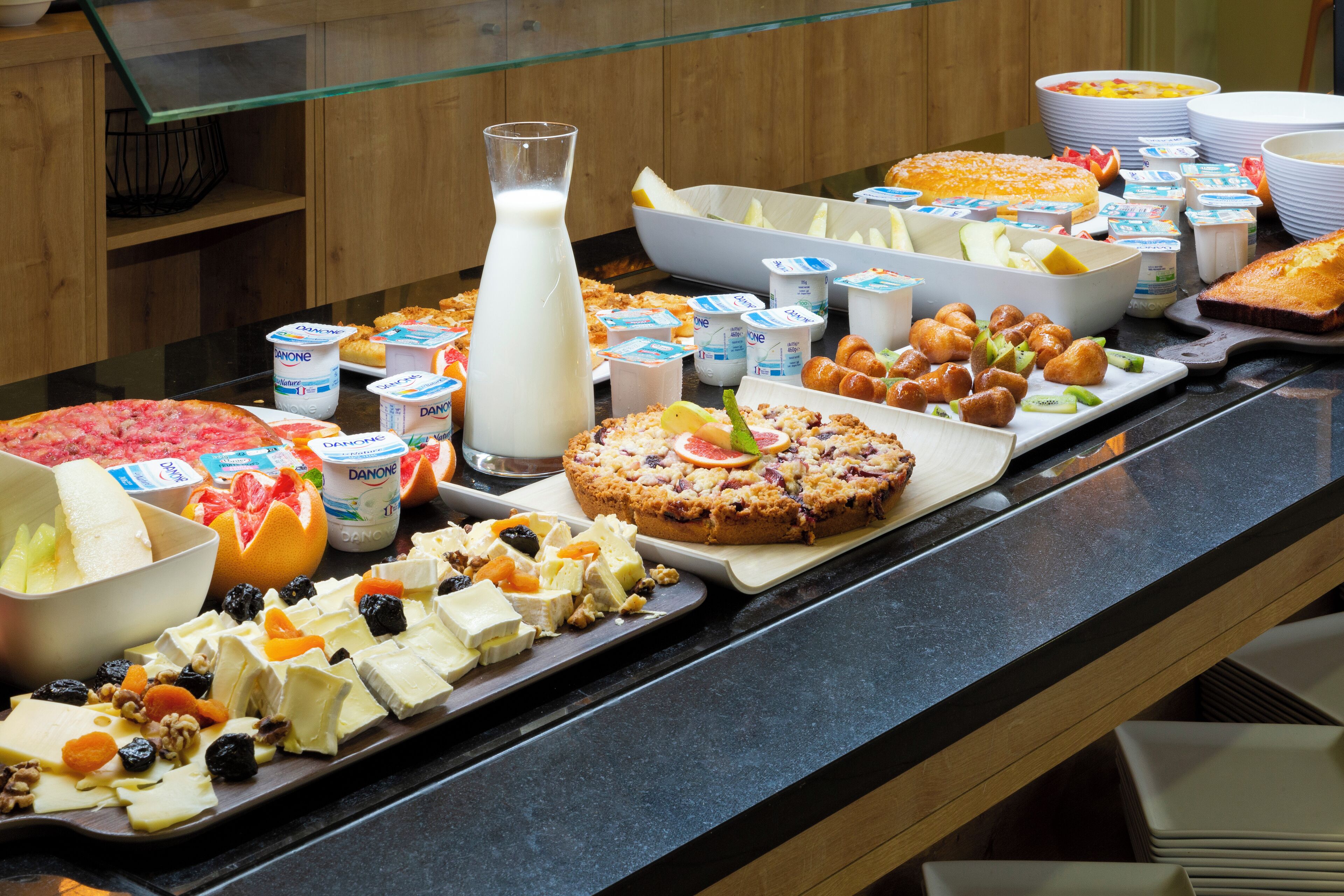 A buffet table with various food items including cheese, fruits, and pastries.
