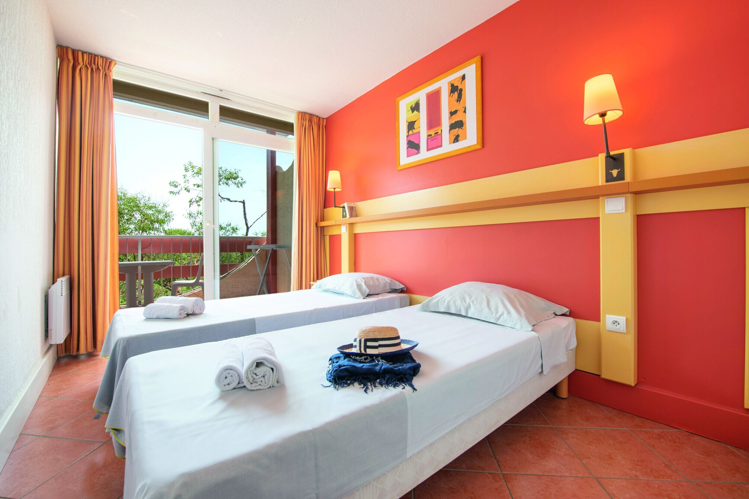 A hotel room with two beds, a balcony, and a red wall.