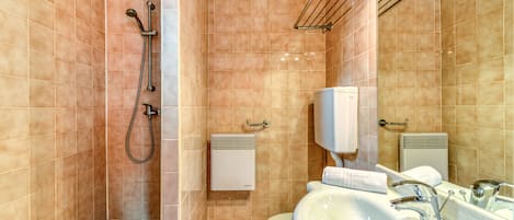 Een badkamer met douche, toilet, wastafel en handdoekhouder.