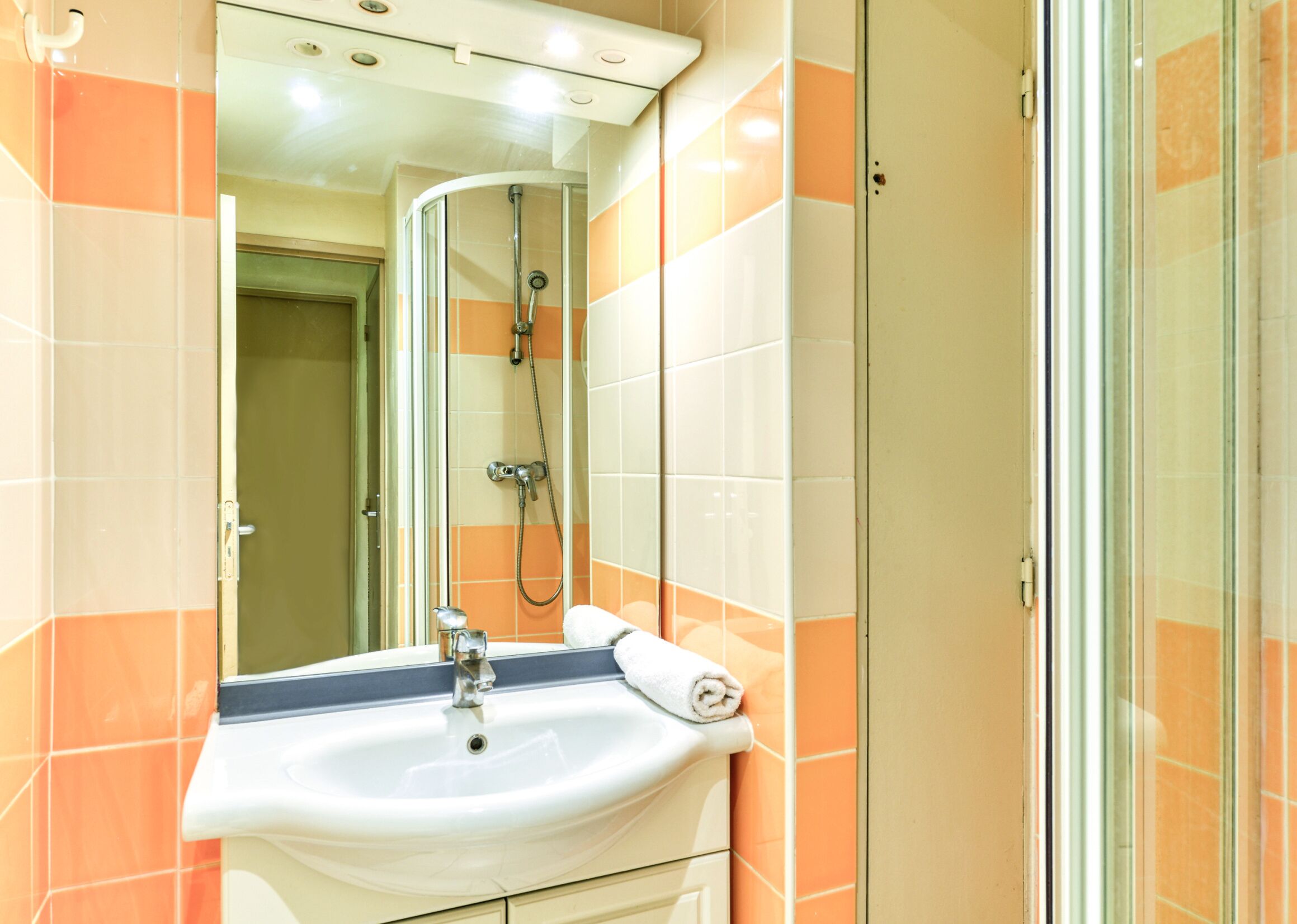 A bathroom with a sink, mirror, and shower.