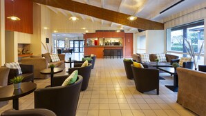 A spacious lobby with multiple seating areas, a reception desk, and large windows providing natural light. - SOWELL RESIDENCES Les Lauriers Roses (Agde)