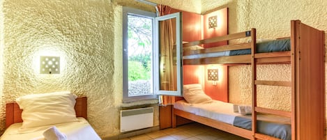 Une chambre avec un lit simple, un lit superposé, une fenêtre avec des rideaux et un luminaire fixé au mur.