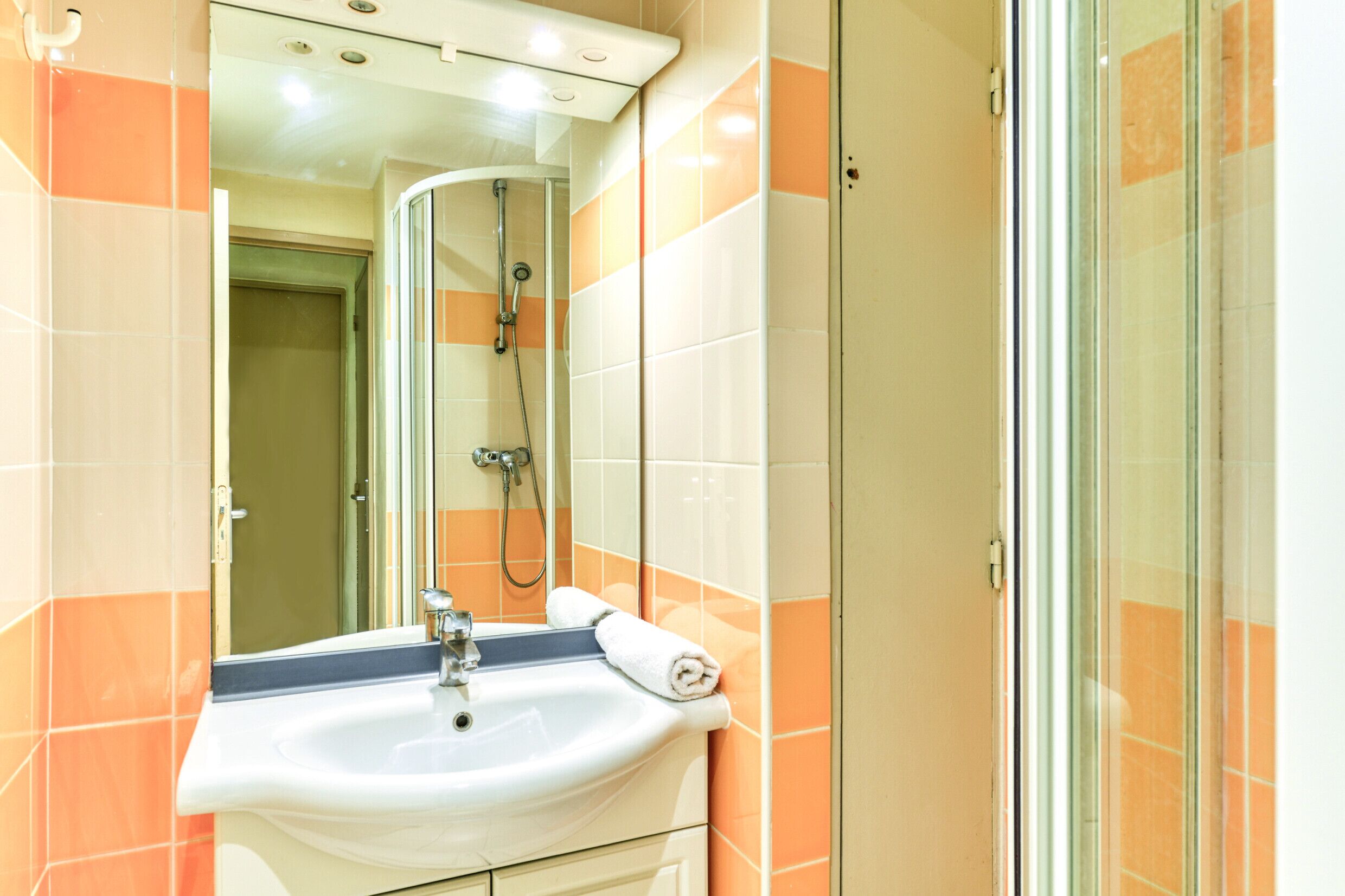 A bathroom with a sink, mirror, and shower.