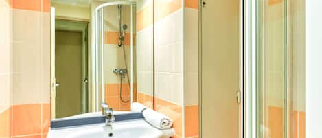 A bathroom with a sink, mirror, and shower.
