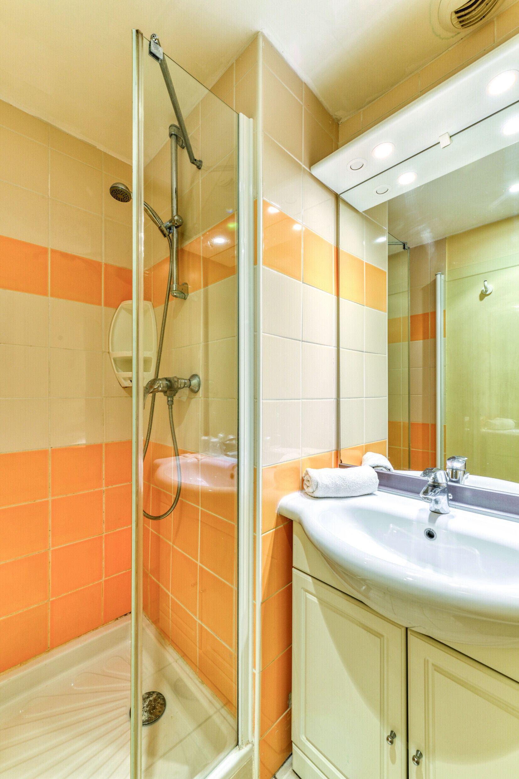 A bathroom with a glass-enclosed shower, a sink, and a mirror.