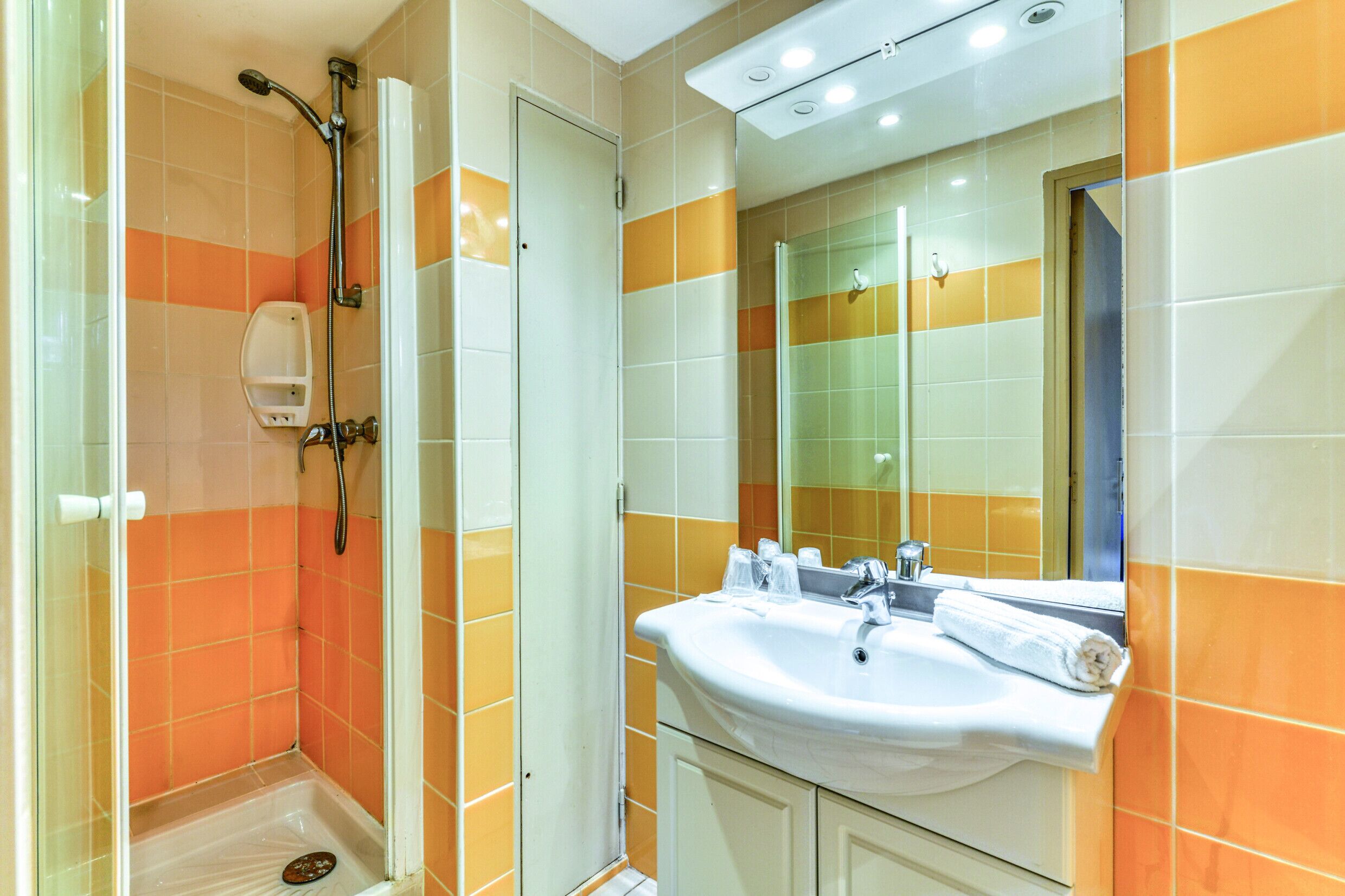 Un baño con ducha, lavamanos y espejo.