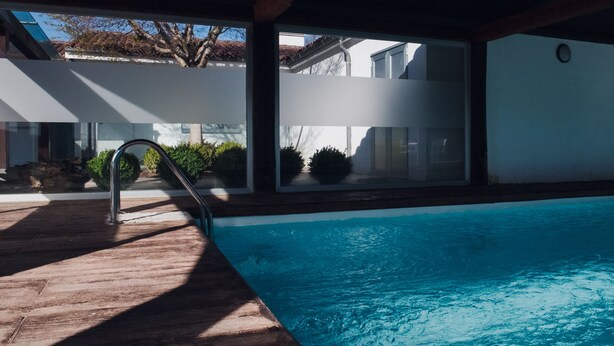 Una piscina interior con cubierta de madera y paredes de vidrio.