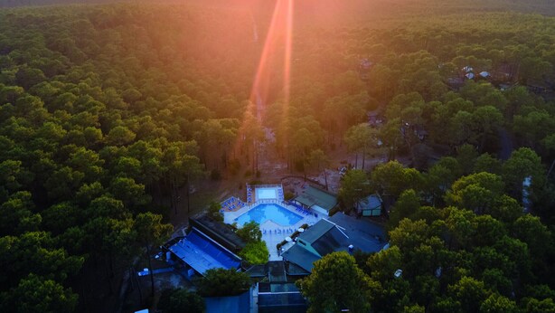 Vista aérea de un resort con piscina, rodeado de bosque denso.