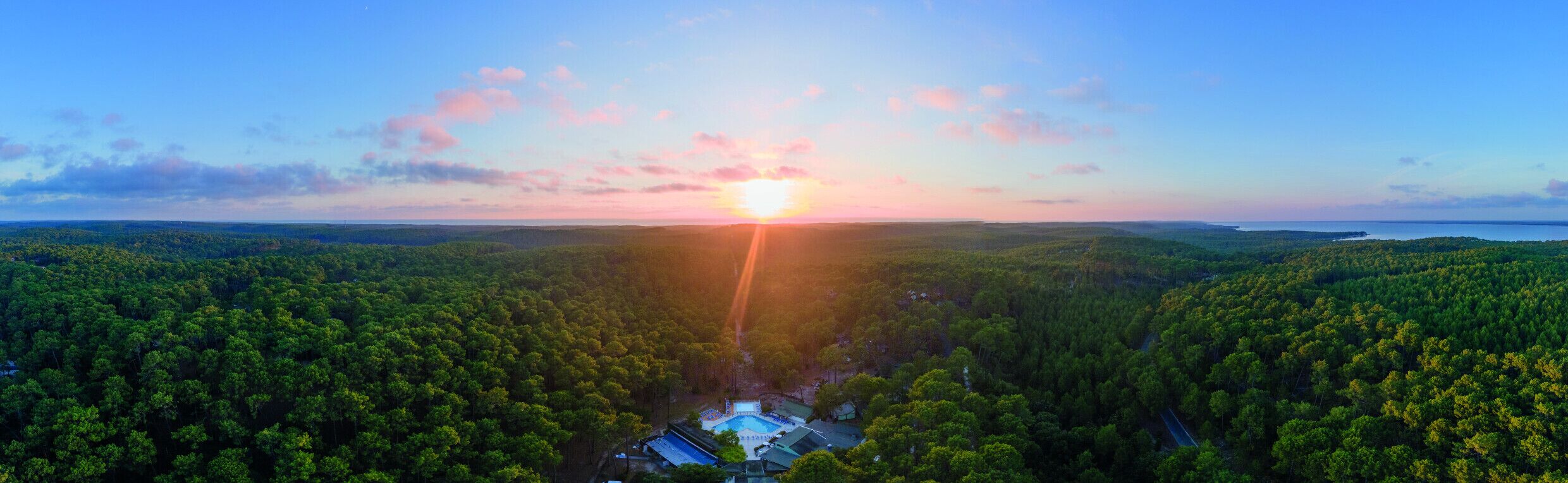 Ett flygbildsbild av ett skogsområde med en klar himmel och en solnedgång.