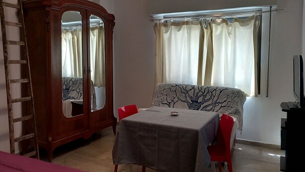 Une pièce comprenant une table à manger, des chaises, une armoire et un téléviseur.