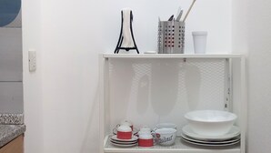 Une étagère en métal blanc contenant des ustensiles et des accessoires de cuisine.