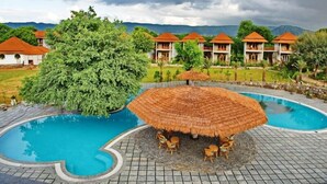 Un complexe hôtelier doté d’une piscine, de parasols en chaume et de plusieurs bâtiments de style bungalow.