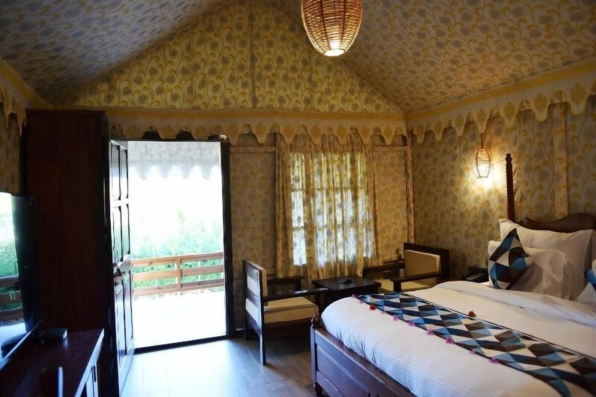 Un dormitorio con cama, escritorio, silla y ventana con cortinas.