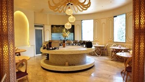 Un hall d’hôtel moderne avec un bar central de forme circulaire, des espaces de détente et un éclairage décoratif.