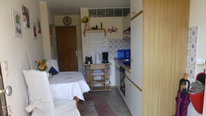 Una habitación compacta con cama, kitchenette pequeña y baño.