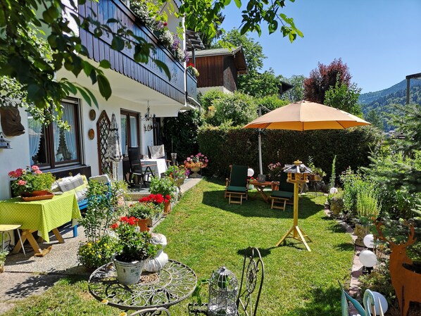 Un jardin bien entretenu, agrémenté d’une terrasse, de coins salon extérieurs et de diverses plantes en pot.