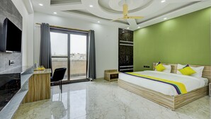 Habitación de hotel moderna con una cama grande, un televisor montado en la pared, un escritorio de madera y vistas a la ciudad a través de la ventana.