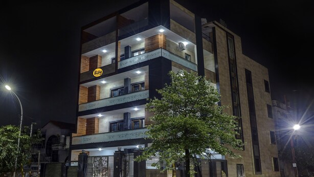 Un edificio de varios pisos con balcones, un logotipo visible y una entrada protegida por una reja.