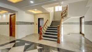 Un interior moderno con una escalera de mármol, una puerta de madera y un diseño geométrico en el suelo.