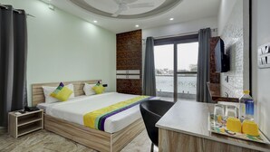 Una habitación de hotel con cama, escritorio, silla, teléfono, botella de agua y vaso.